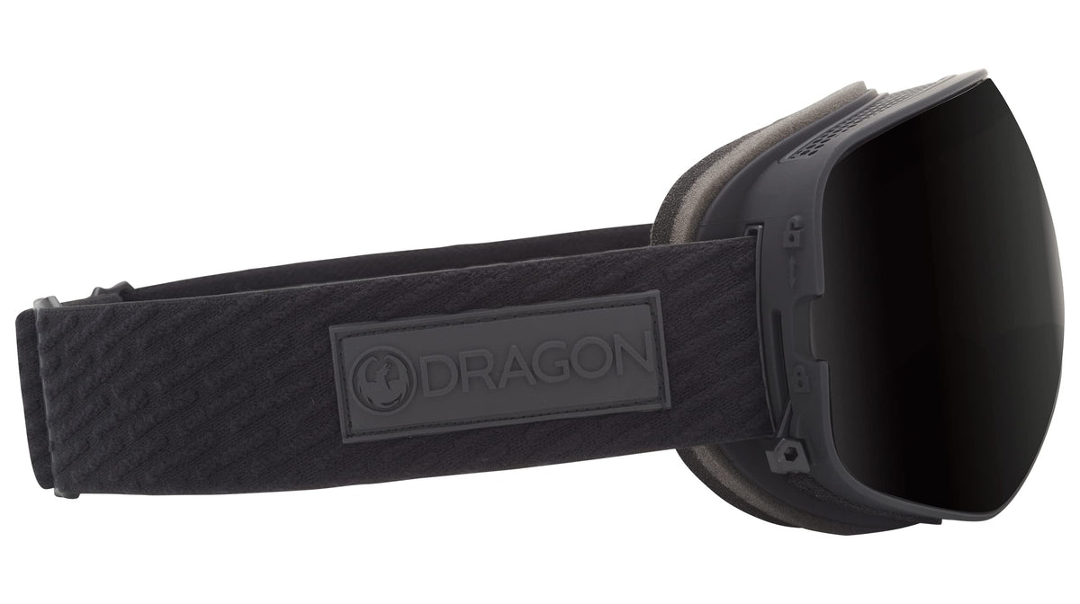 Black snow goggles with dark lens, padded strap and DRAGON logo badge at center