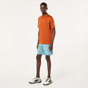 Men's orange polo shirt worn by model with short sleeves and chest logo