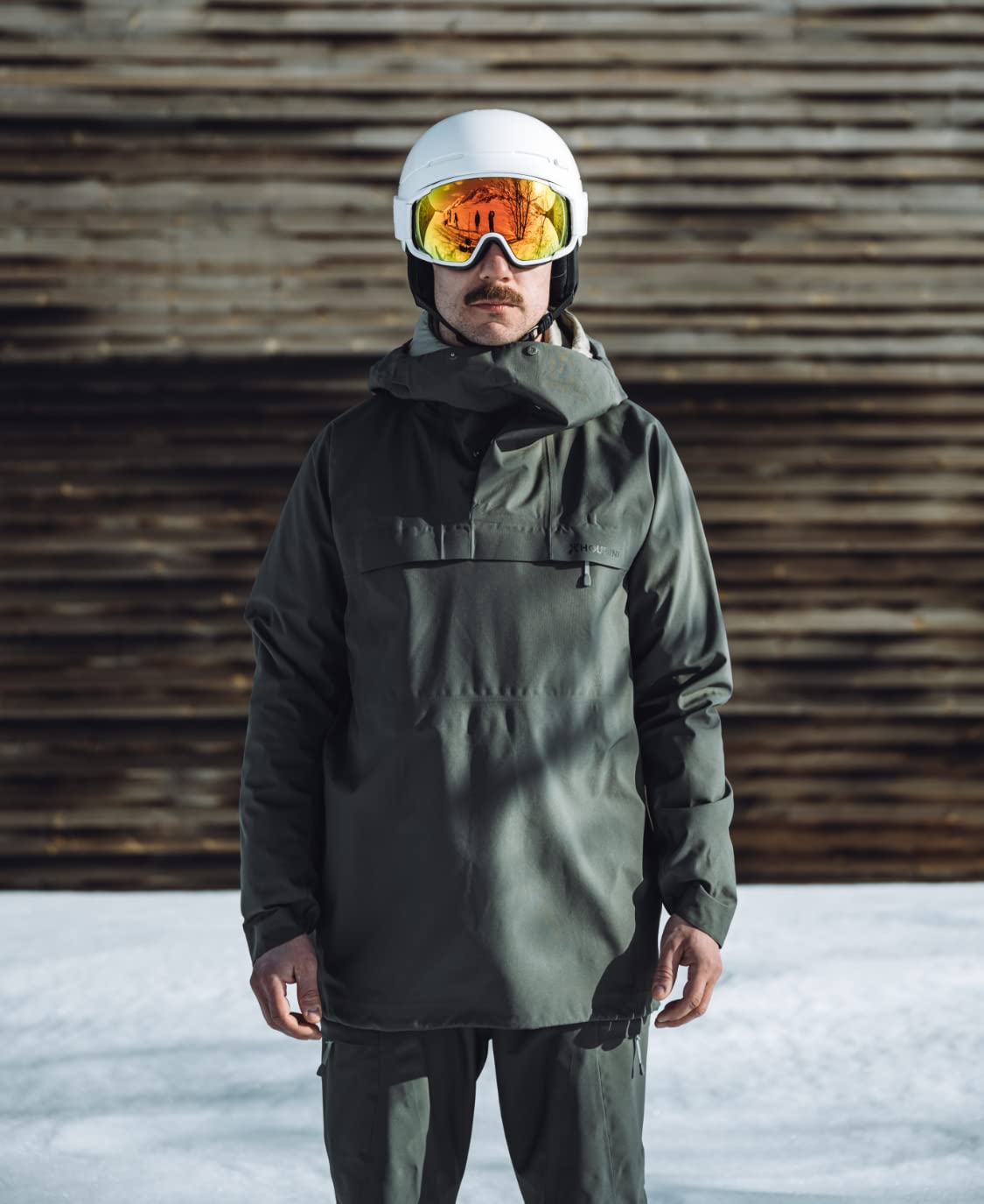 White ski goggles on helmet with orange mirrored lens and black strap