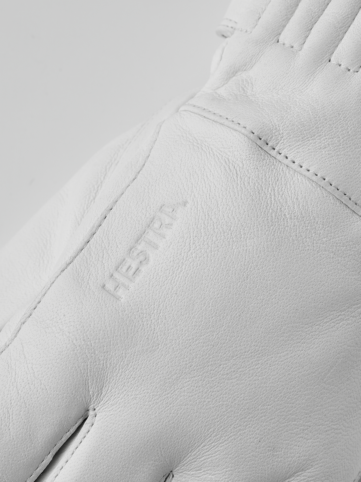 White leather glove with embossed brand patch on back and side seam stitching