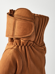 Tan leather gloves with curved wrist strap, ribbed cuff, and gathered back