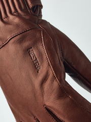 Brown leather gloves with embossed logo and double-stitched finger seams