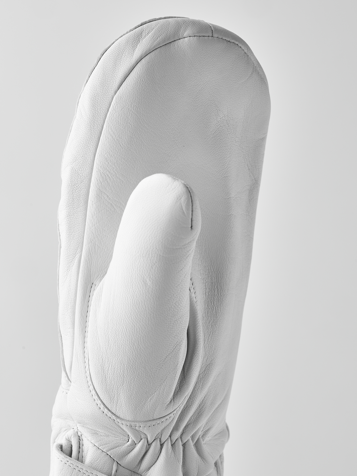 White wool mitten with rounded finger shape and ribbed cuff at wrist