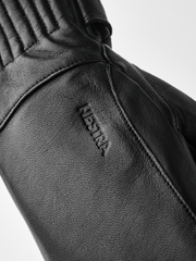 Black wool mittens detail, Hestra logo on textured leather wrist seam