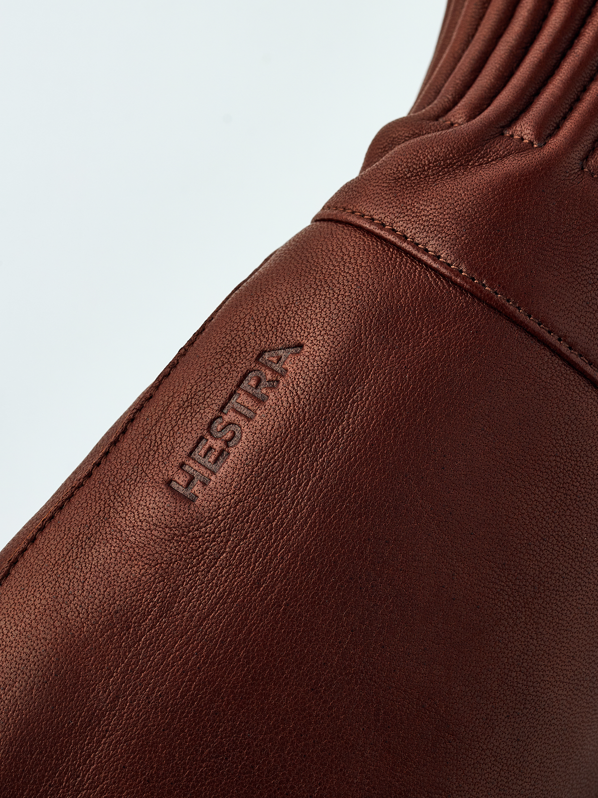 Brown wool mitten detail with Hestra logo embossed on outer wrist area