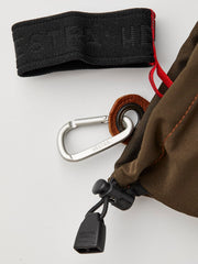 Cuff loop attachment and drawcord on dark olive glove with red inner thread detail.