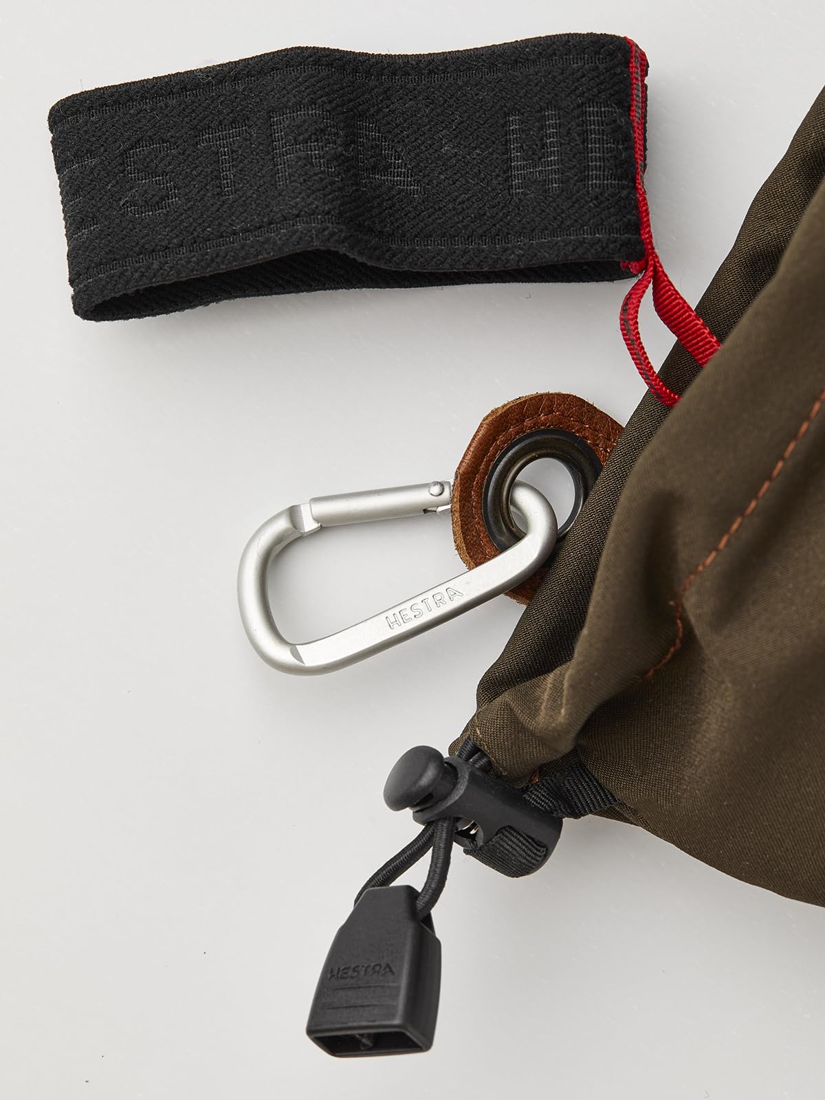 Cuff loop attachment and drawcord on dark olive glove with red inner thread detail.