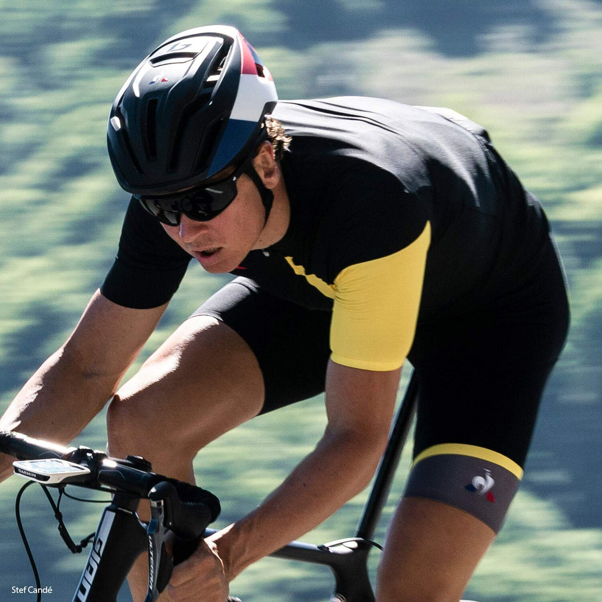 White, red, and blue road bike helmet worn by cyclist with black chin strap