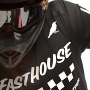 Black long-sleeve motocross jersey chest detail with checkered stripe and text logo