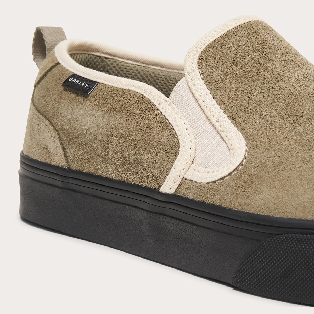 Suede slip-on sneaker with white side strap, tan heel panel, black rubber sole