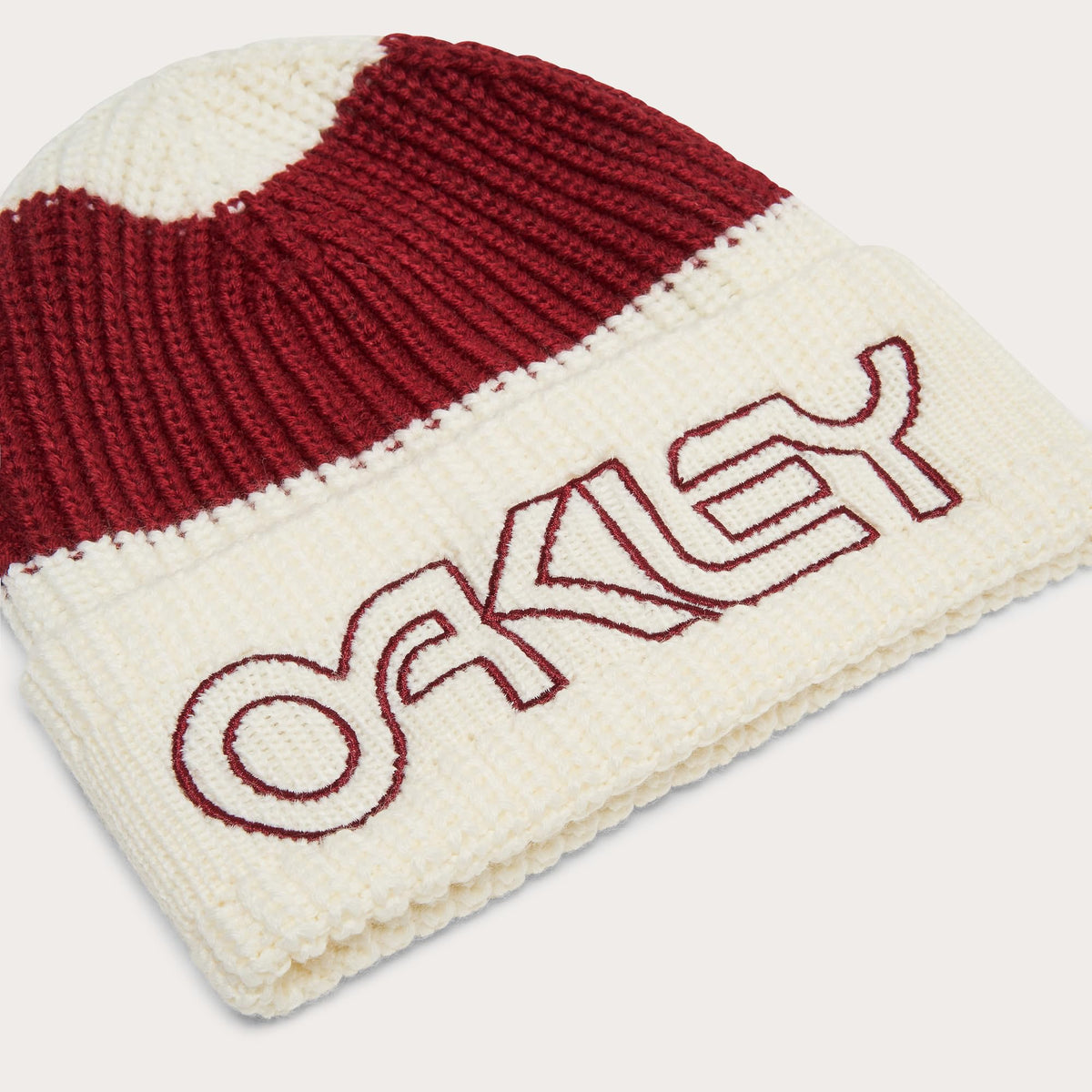 Folded knit beanie with cream base, dark red stripe, and 'Oakley' logo