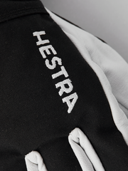 Black ski junior glove with white HESTRA text on back of hand