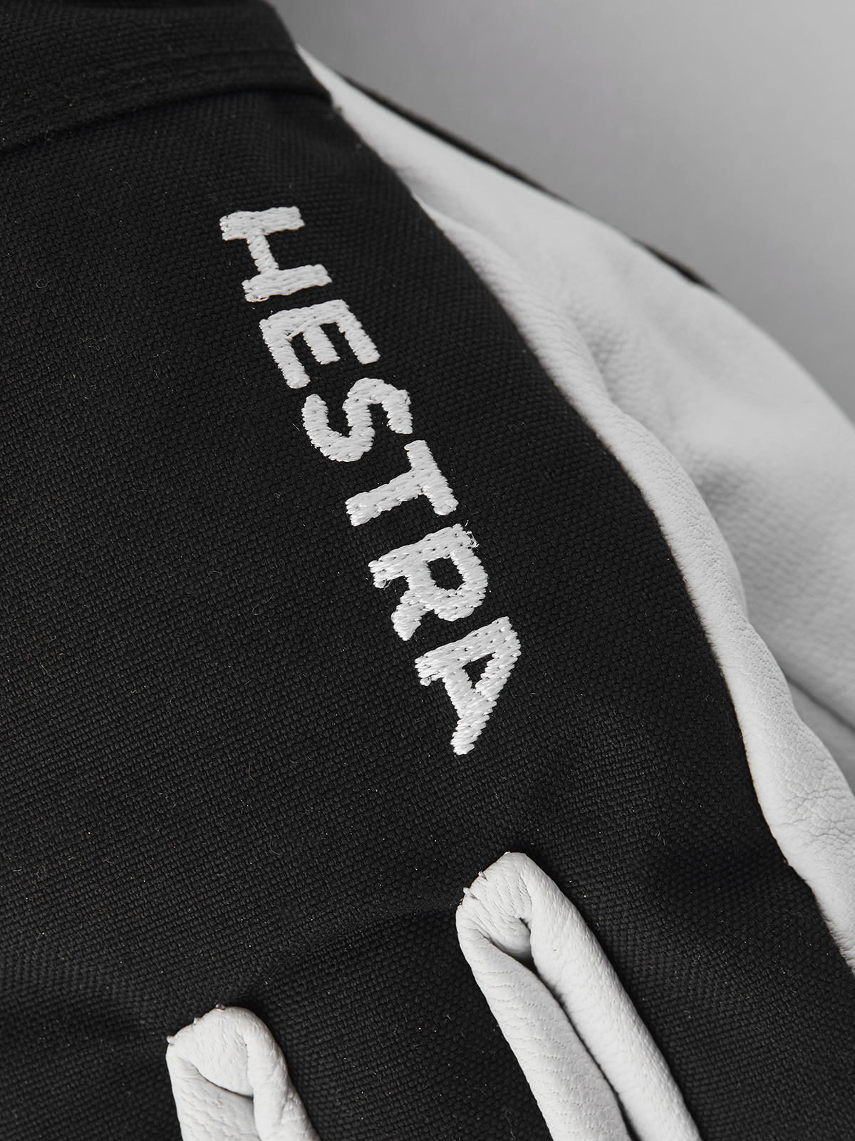 Black ski junior glove with white HESTRA text on back of hand