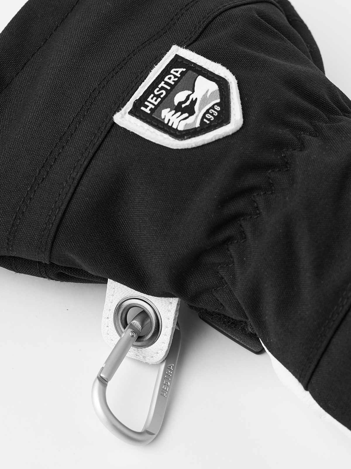 Black ski glove with Hestra patch and metal carabiner loop on the cuff
