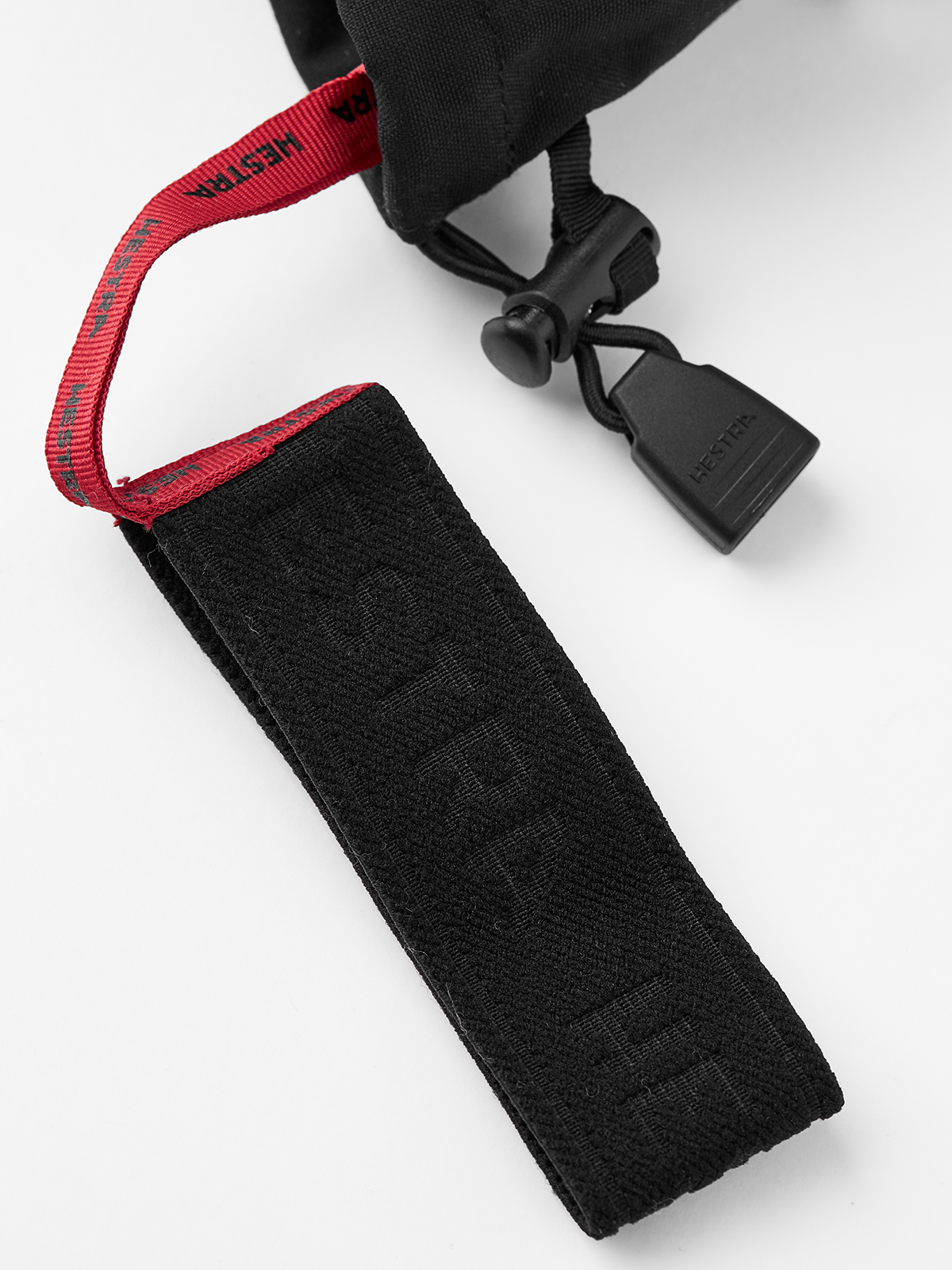 Black ski glove with red wrist strap detail and toggle closure on cuff.