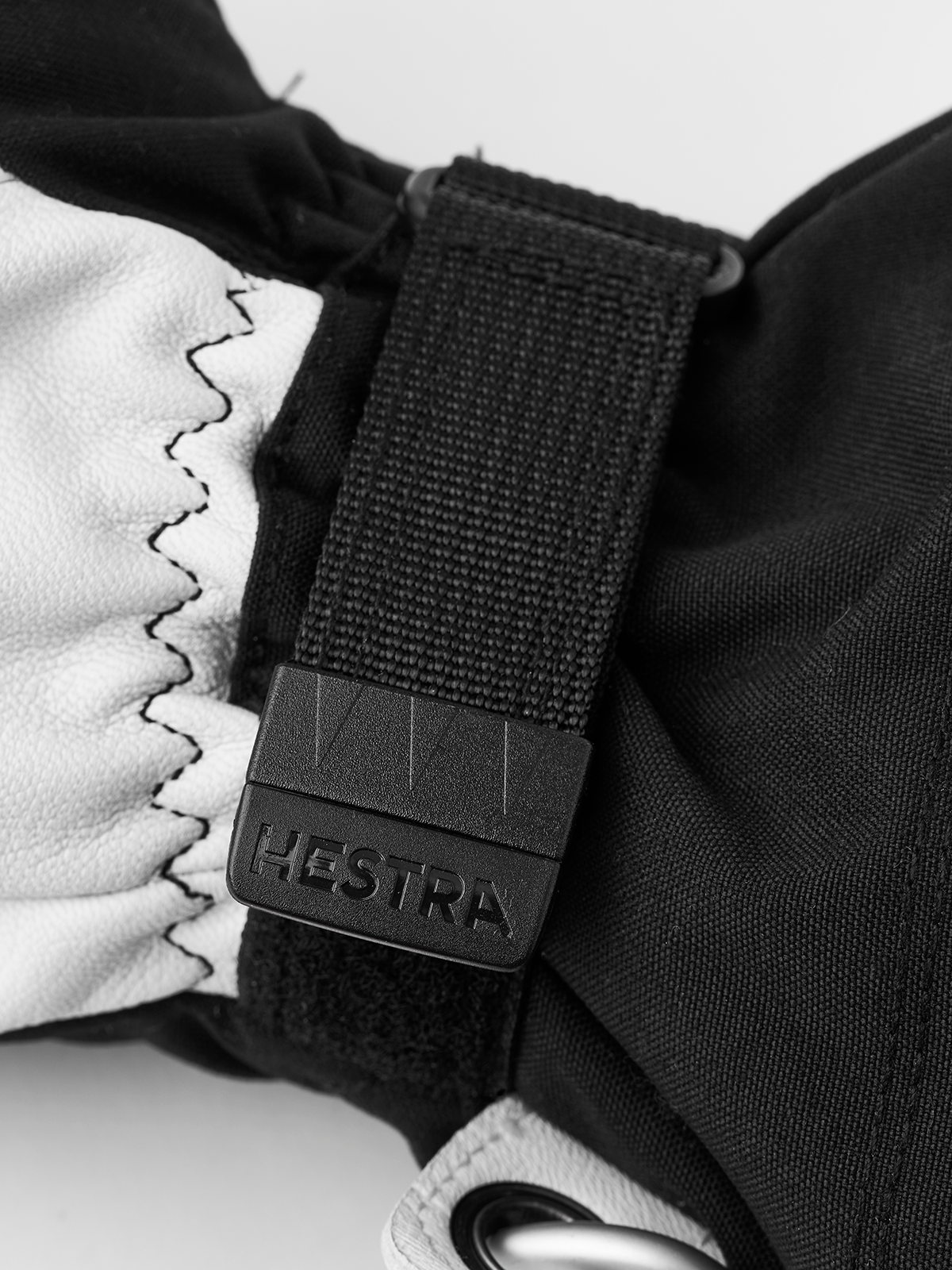 White and black ski glove with black strap and engraved HESTRA label
