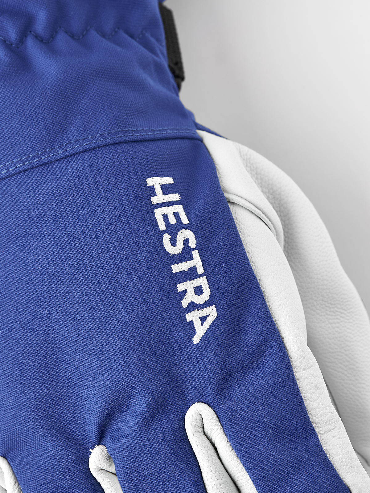 Royal blue ski glove with Hestra logo on the wrist and white leather interior.