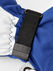 Blue and white ski glove with black webbing strap and Hestra logo tag