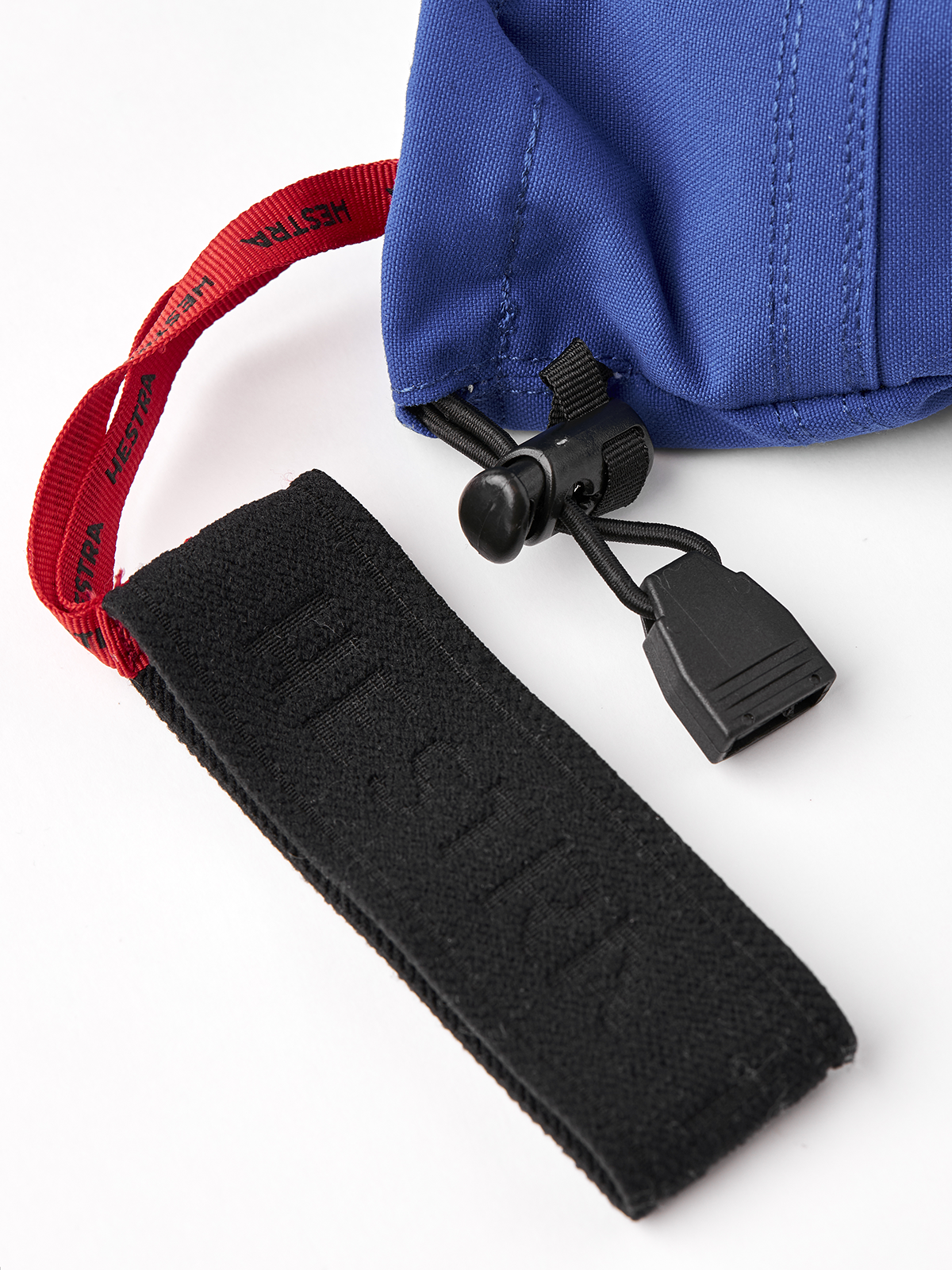 Blue glove cuff with red strap webbing and black pull-tab closure