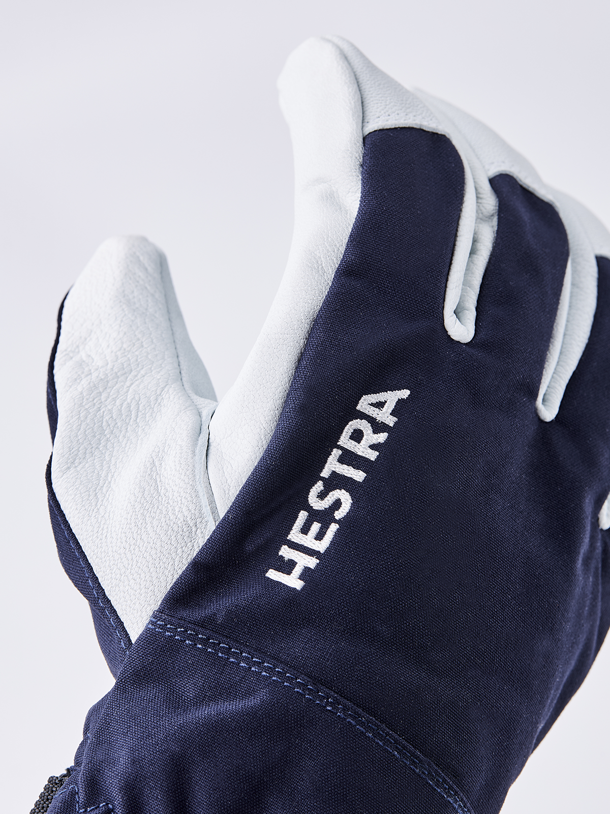 Navy ski glove with white leather panels and HESTRA lettering on cuff