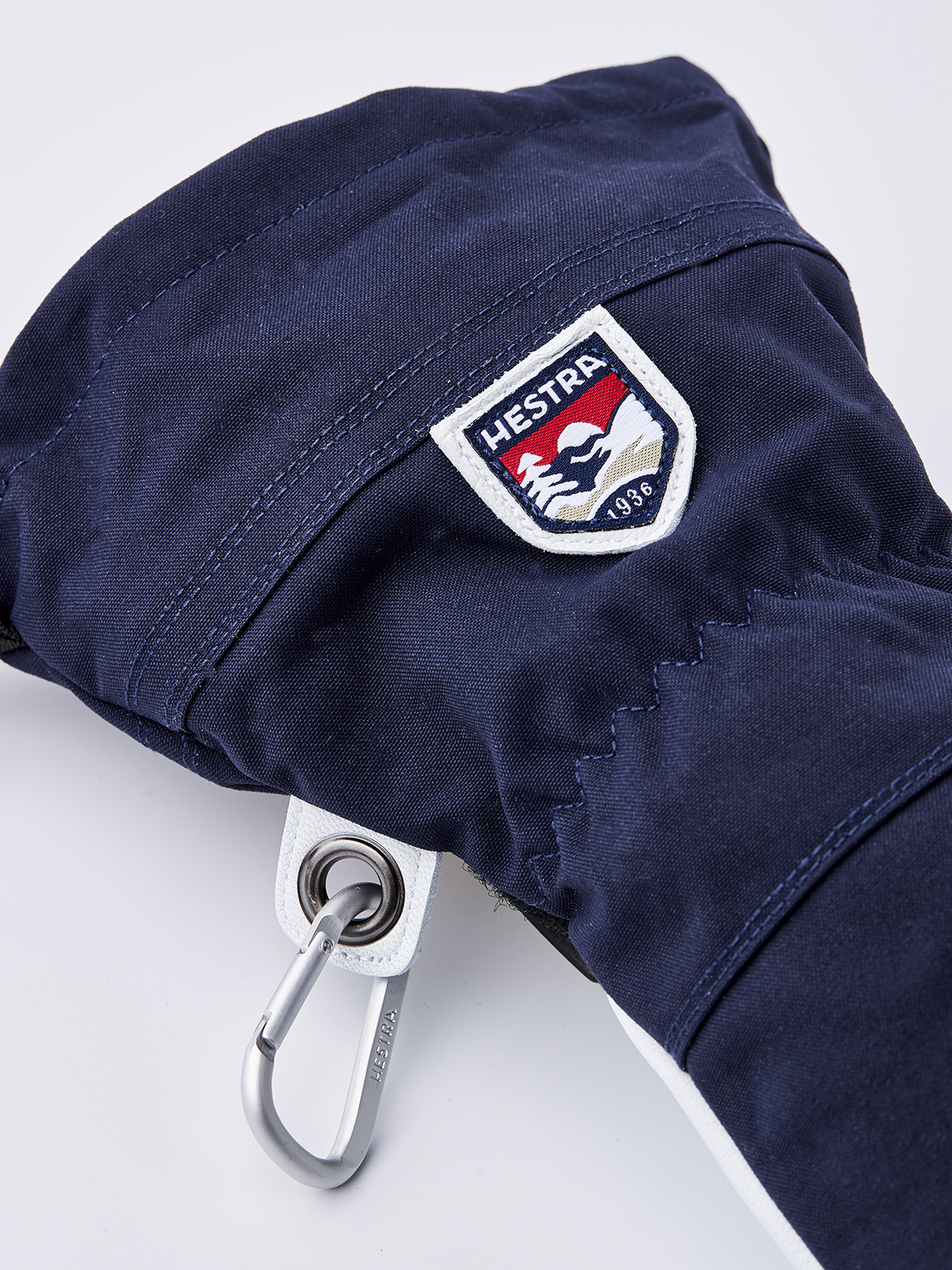 Navy ski glove with Hestra shield patch and metal ring carabiner.