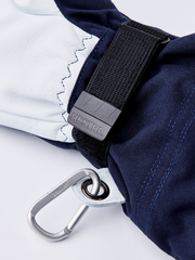 Navy and white ski glove close-up with black strap, Hestra tag, and metal loop