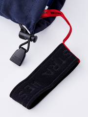 Navy ski glove wrist strap with black fabric keeper and red drawcord.