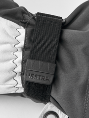 Gray ski glove with black wrist strap and “Hestra” logo patch detail.