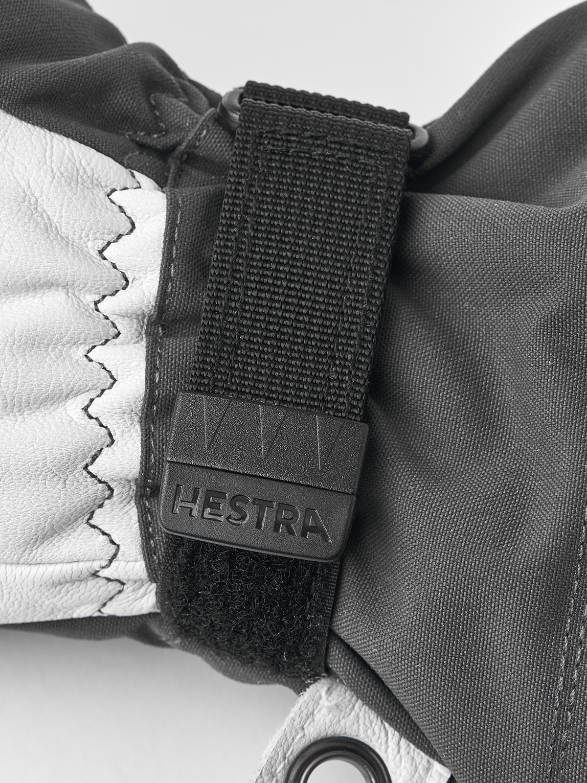 Gray ski glove with black wrist strap and “Hestra” logo patch detail.