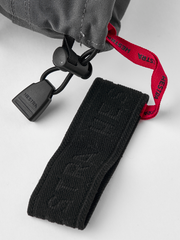 Black ski gloves with textured wrist patch and black adjuster strap with red webbing