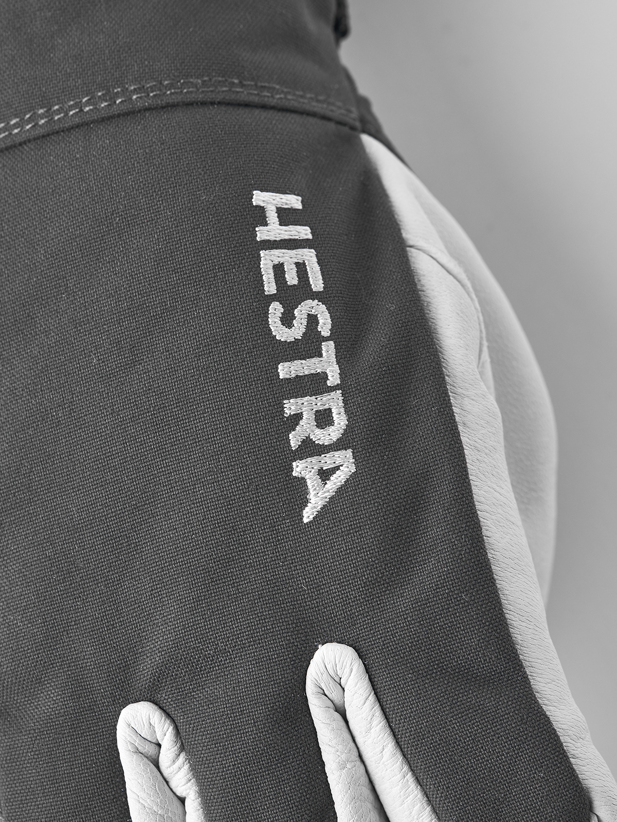 Gray ski glove with vertical HE STRA text on the back of the hand