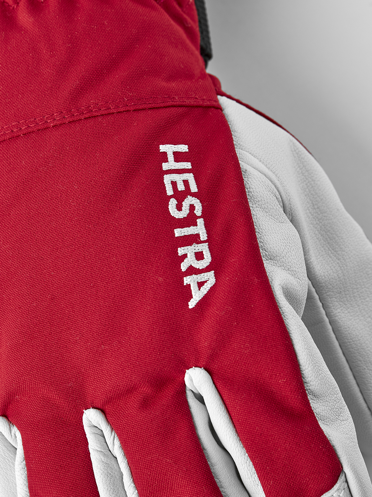 Red ski glove with Hestra logo print and white leather backhand panels.