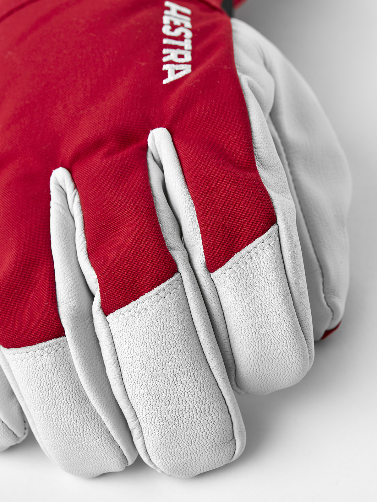 Red ski gloves with light gray leather palms and padded fingers with white stitching