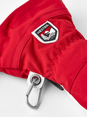 Red ski glove with Hestra logo patch and metal carabiner clip.