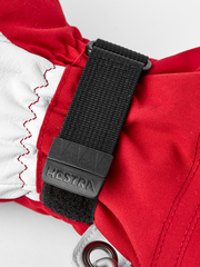 Red and white ski glove close-up with black wrist strap and metal carabiner clip