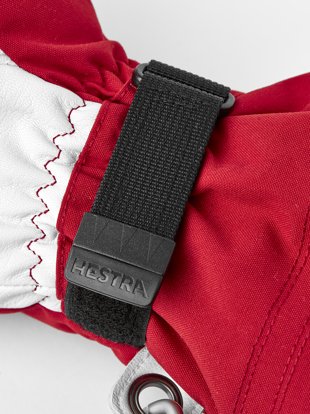 Red and white ski glove close-up with black wrist strap and metal carabiner clip