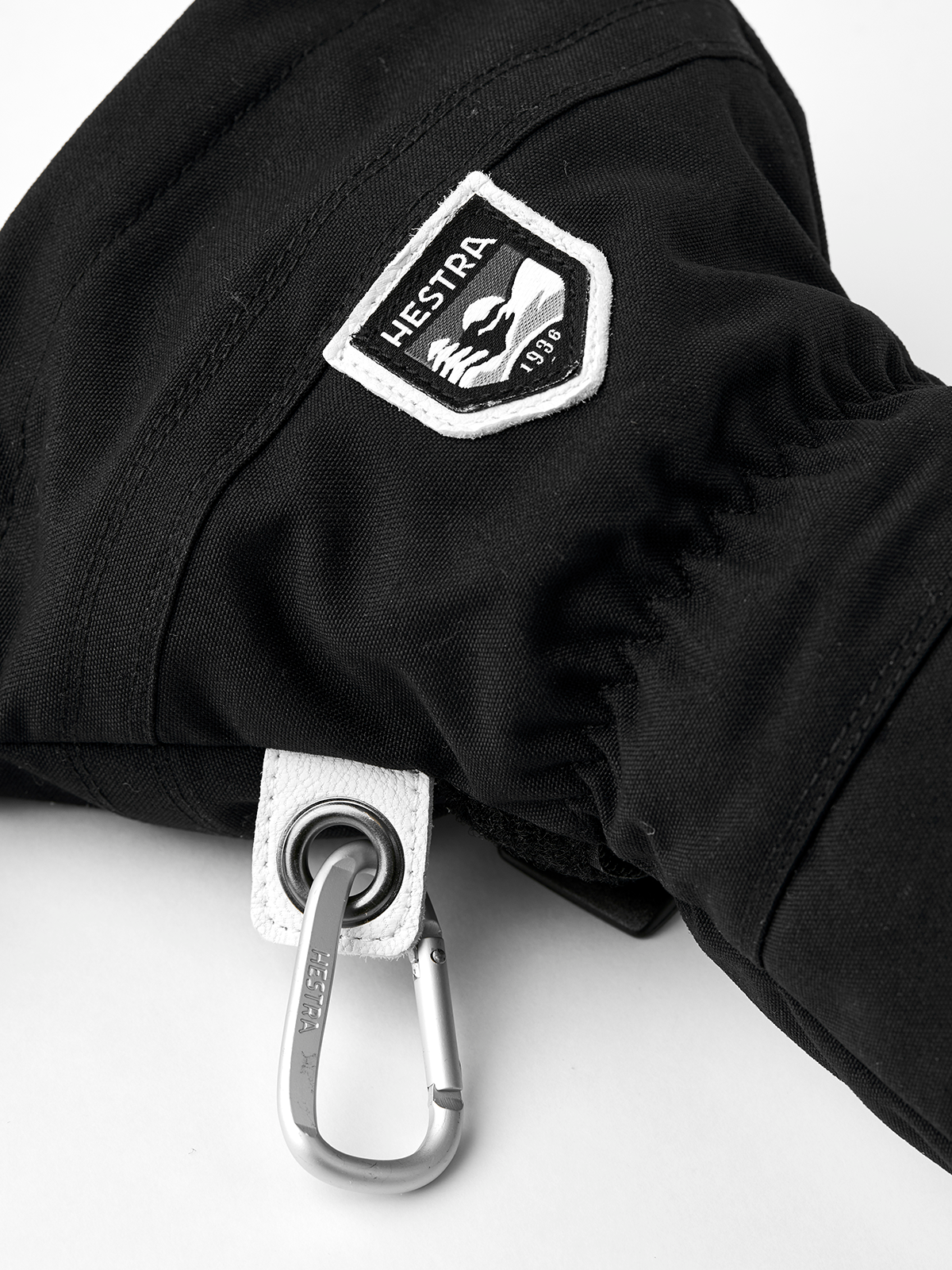 Black ski mitten with Hestra shield patch and metal carabiner wrist clip