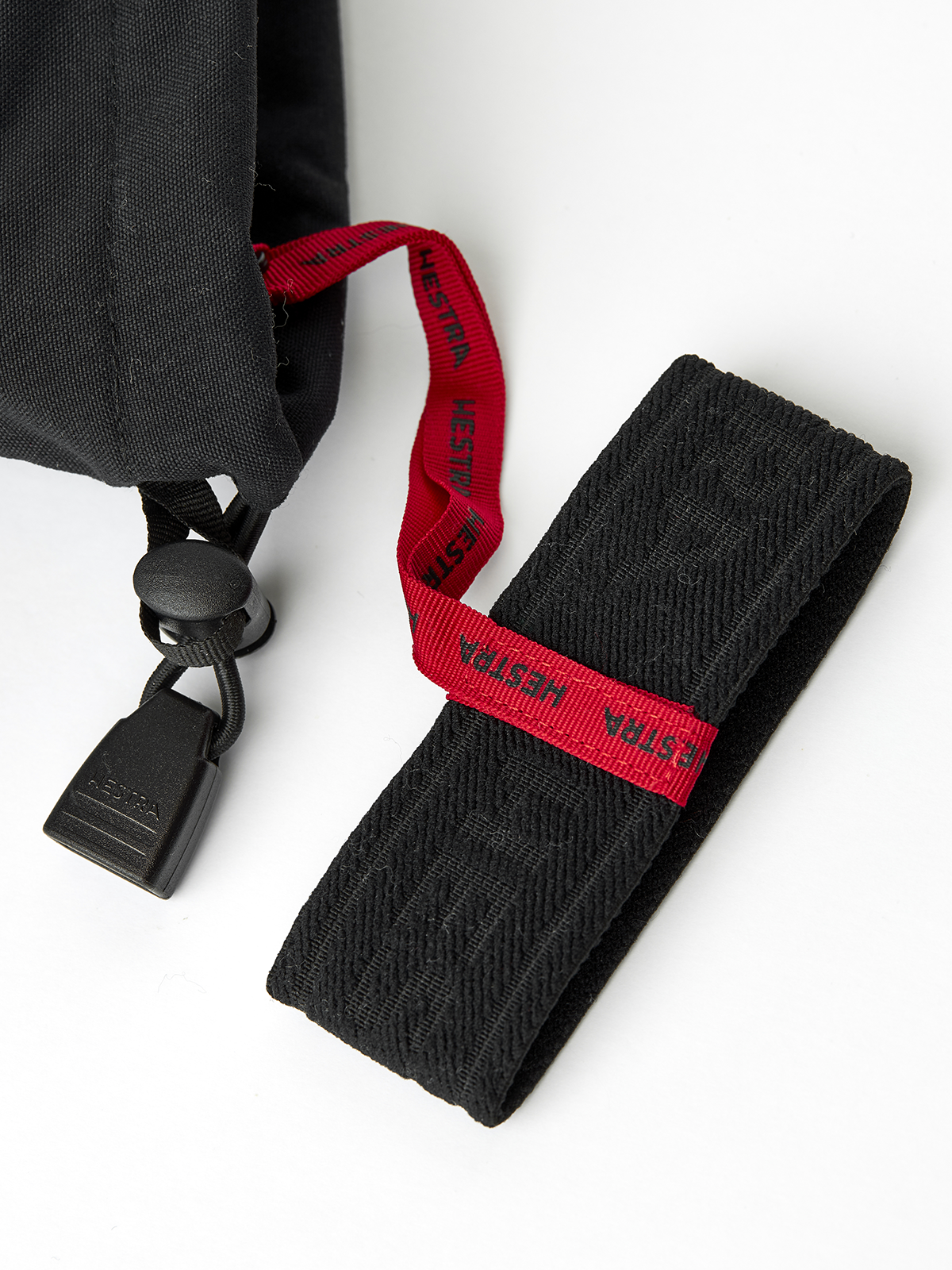 Black Hestra ski glove with red branded hanging loop and black webbing strap