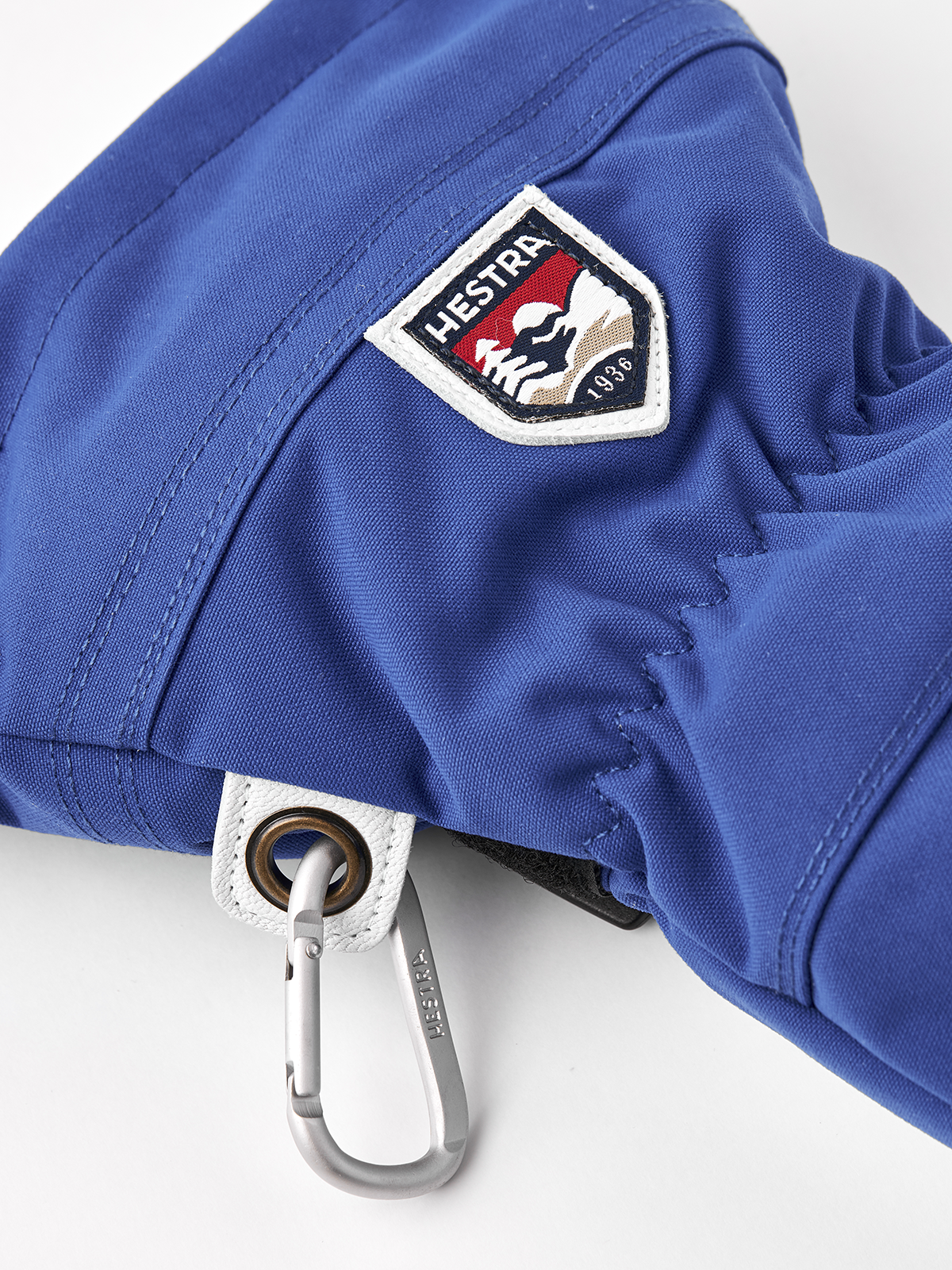 Blue ski mitten with HESTRA shield patch and metal carabiner clip on cuff