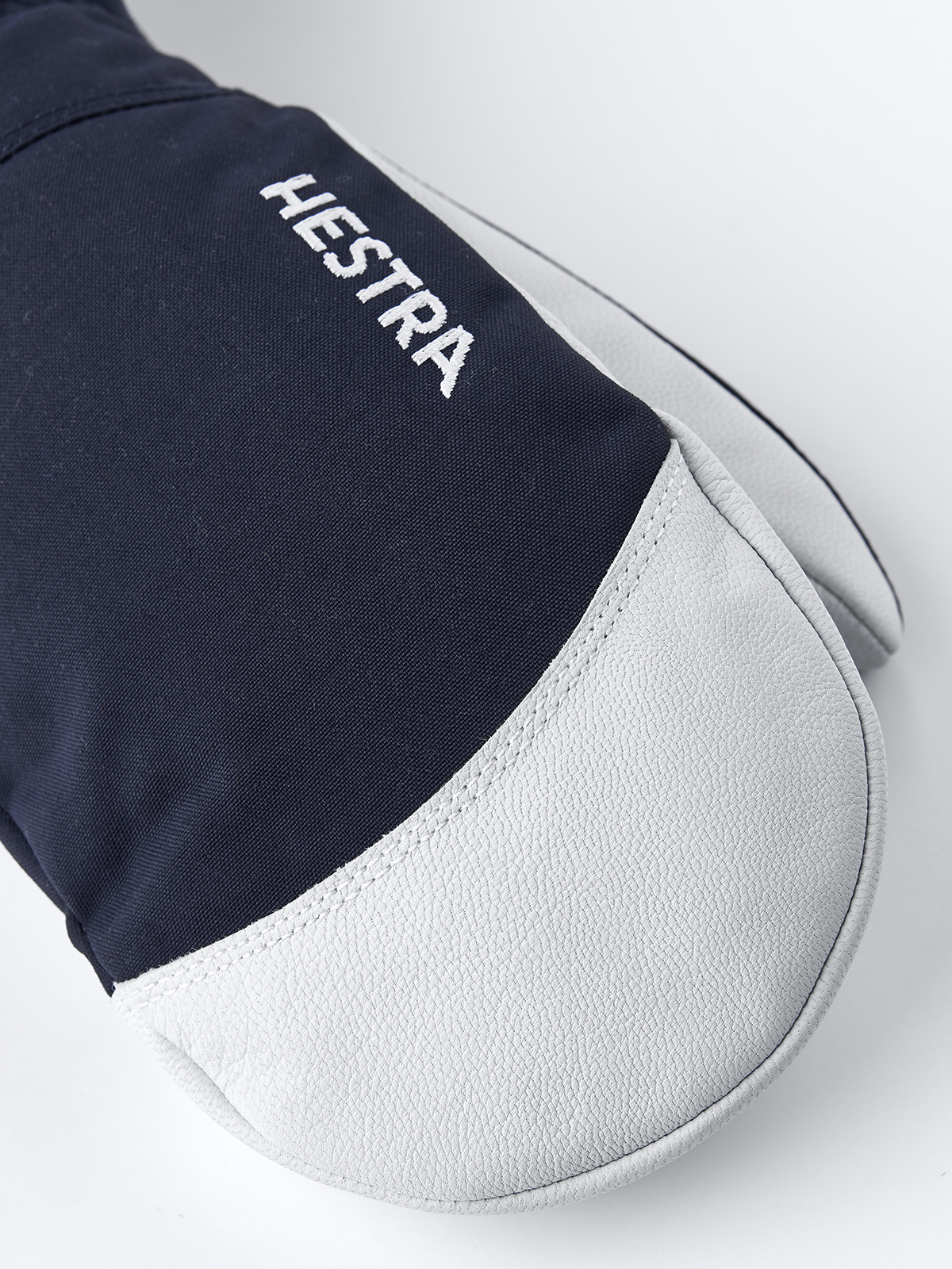 Dark navy and white ski mitten with embroidered HESTRA logo on back