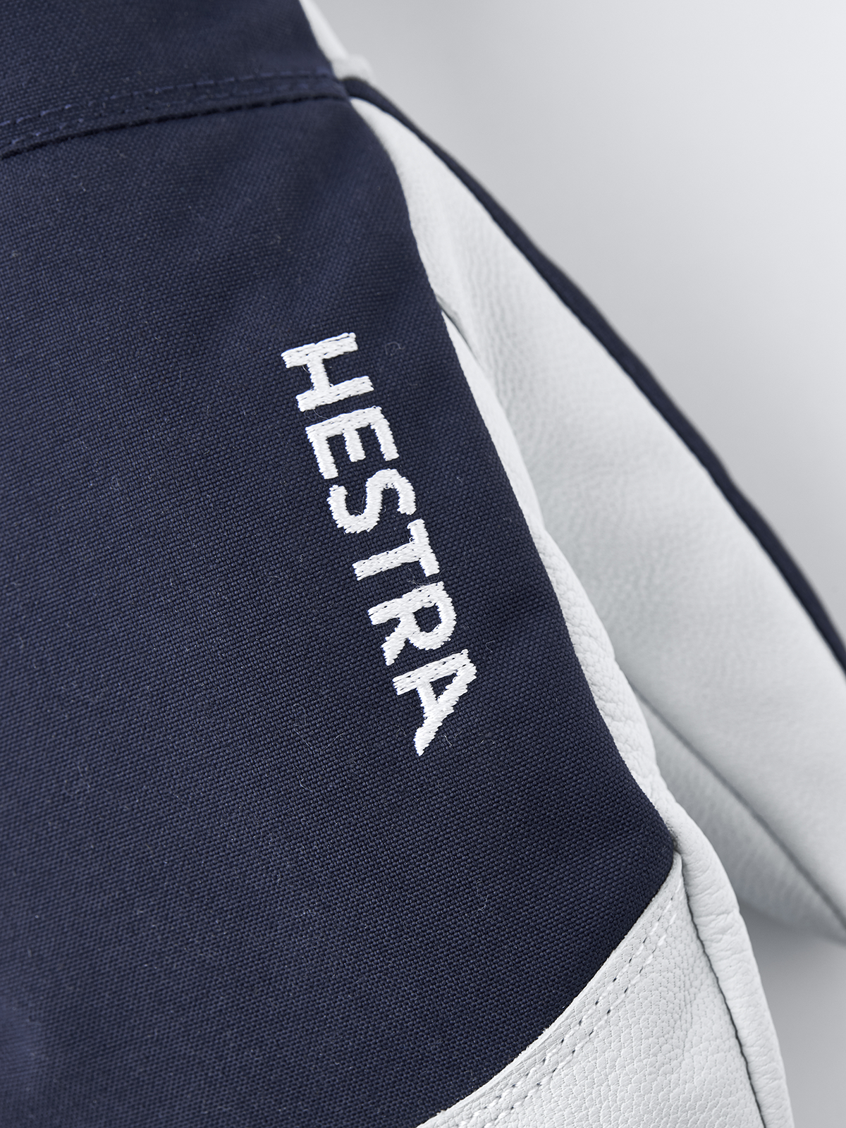 Navy Hestra ski mittens with white leather palm and embroidered logo text