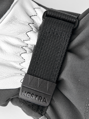 Black and white ski mitten with textured strap and Hestra wrist label
