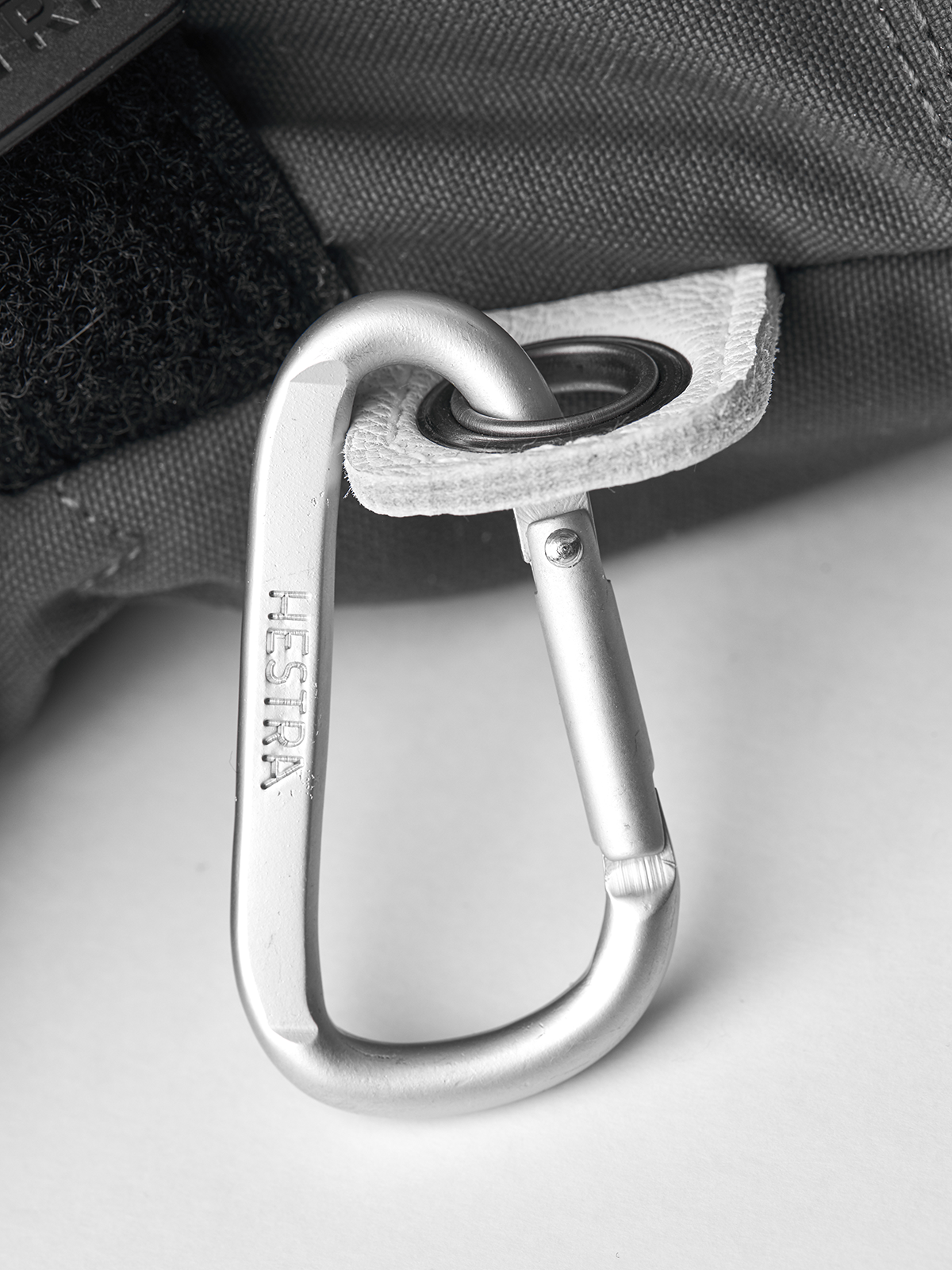 Metal carabiner clip attached to mitten loop on back of glove