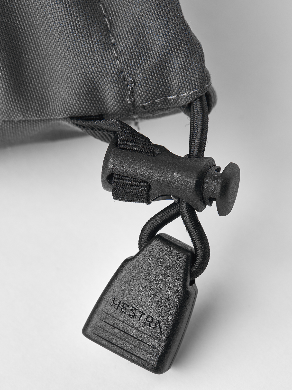 Grey Hestra ski mittens with black cord lock and fastening strap at wrist
