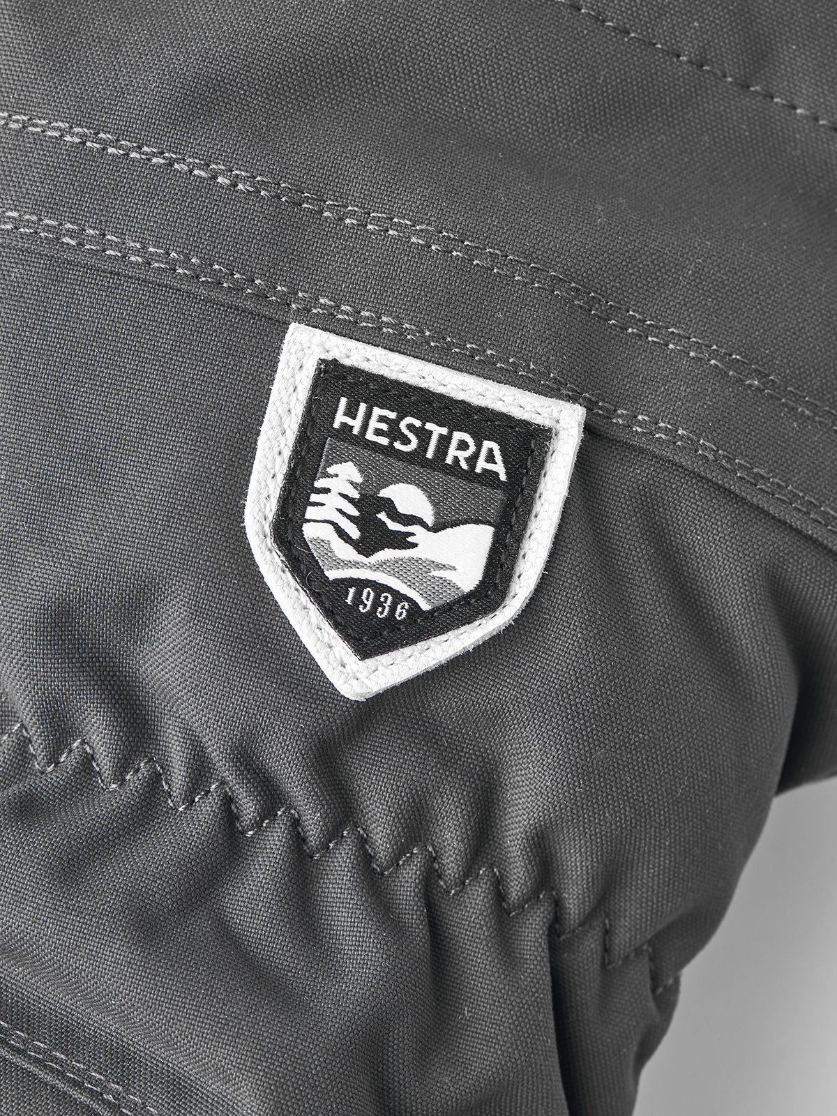 Gray ski mitten with embroidered HESTRA shield logo patch on back panel