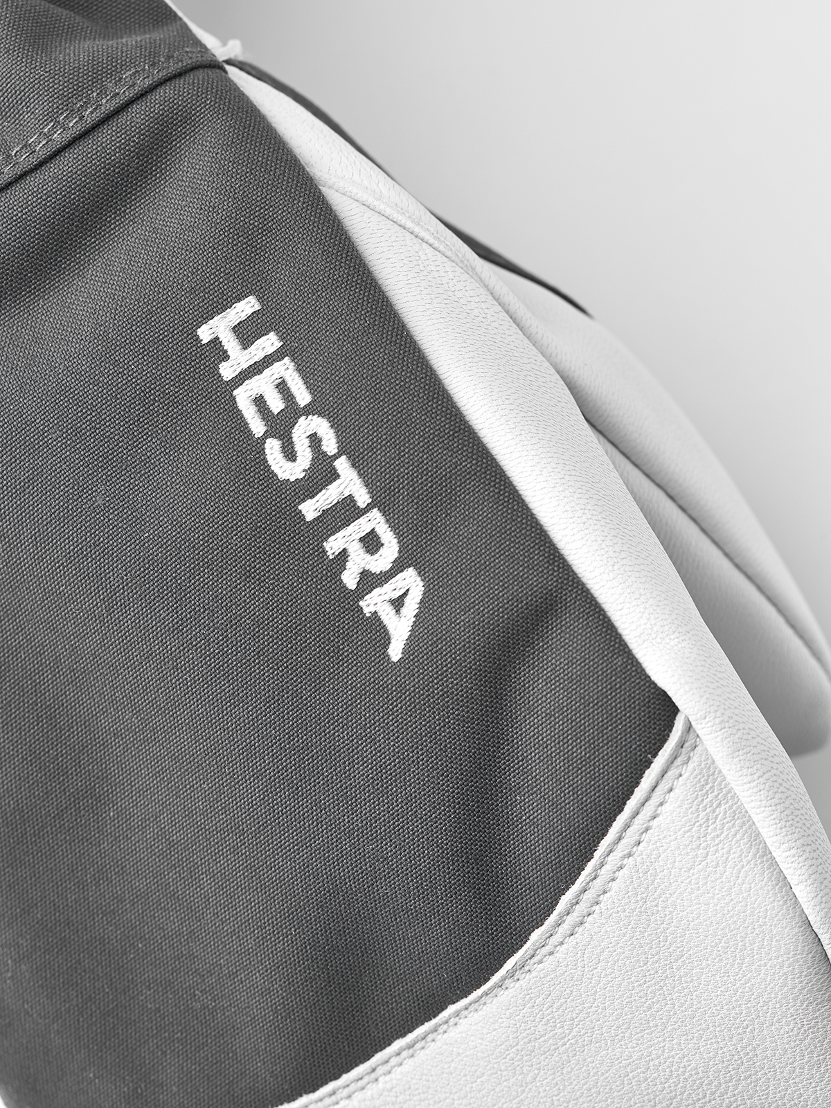 Grey ski mitten with white leather palm and Hestra logo text on fabric