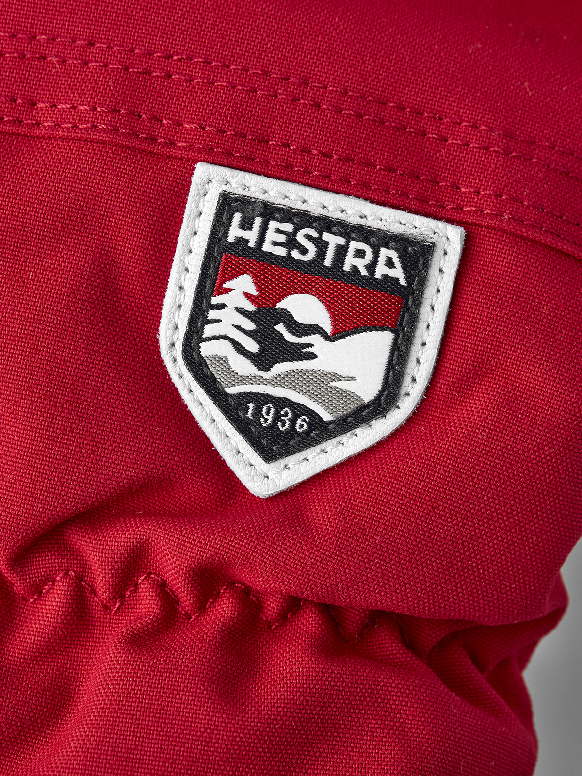 Red Hestra ski mittens with white-trim logo patch on the back