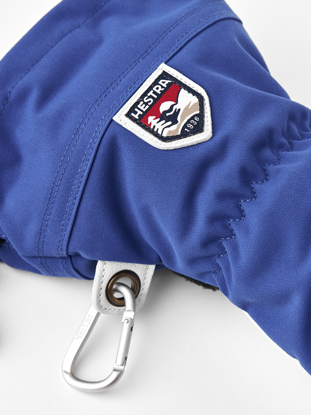 Royal blue Hestra ski glove with logo patch and metal carabiner-style clip