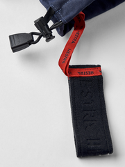 Ski glove cuff detail with red HESTRA webbing loop and dark fabric strap.