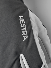 Dark grey 3-finger ski glove with white Hestra text and light leather palm